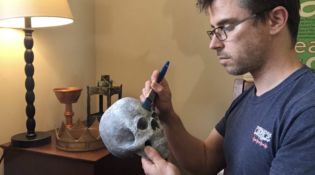 Eric Hart paints a prop skull in his home.